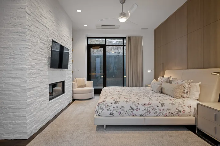 Bedroom with access to exterior, a ceiling fan, and a multi sided fireplace