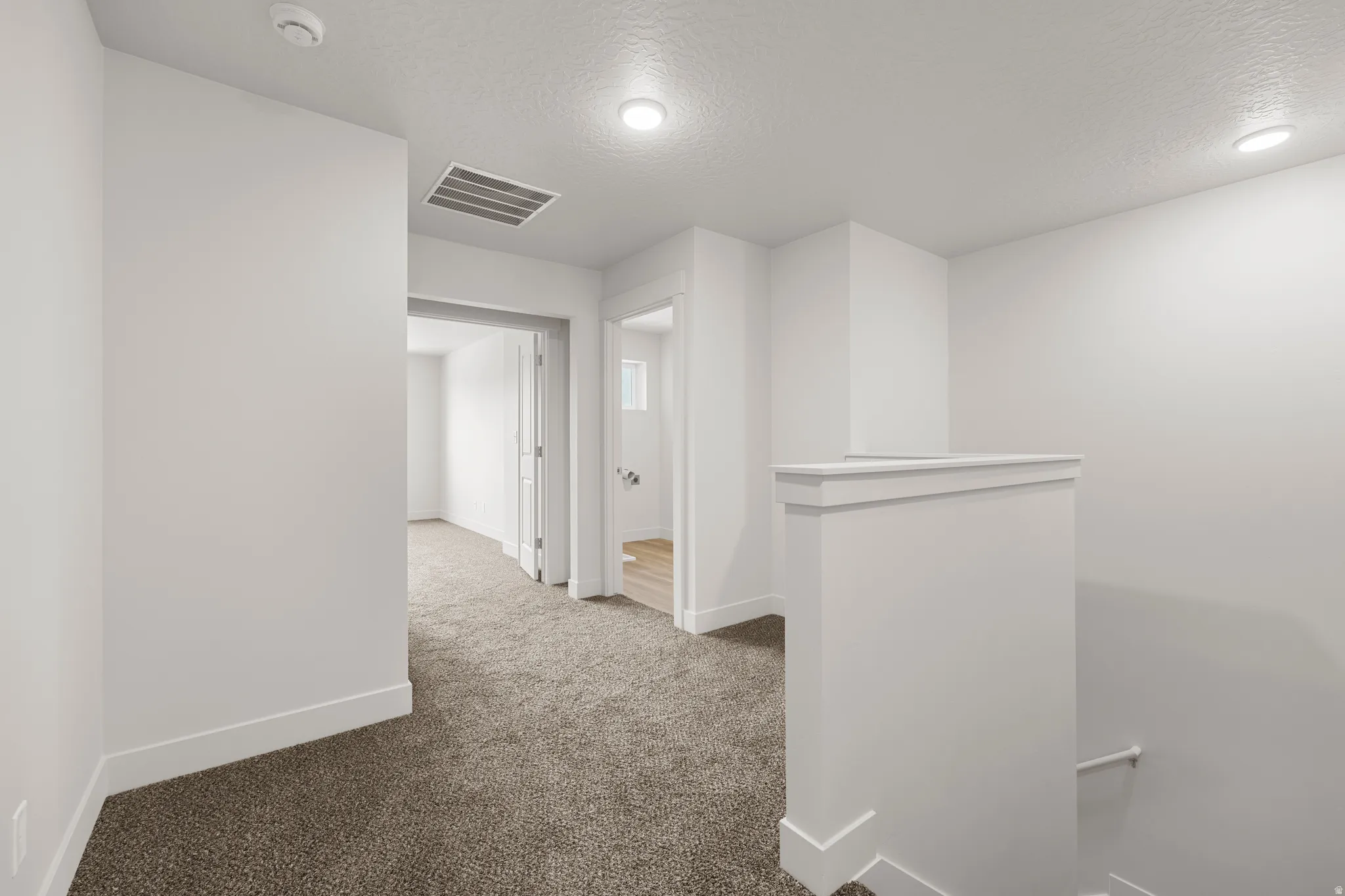 Corridor with an upstairs landing, a textured ceiling, and carpet