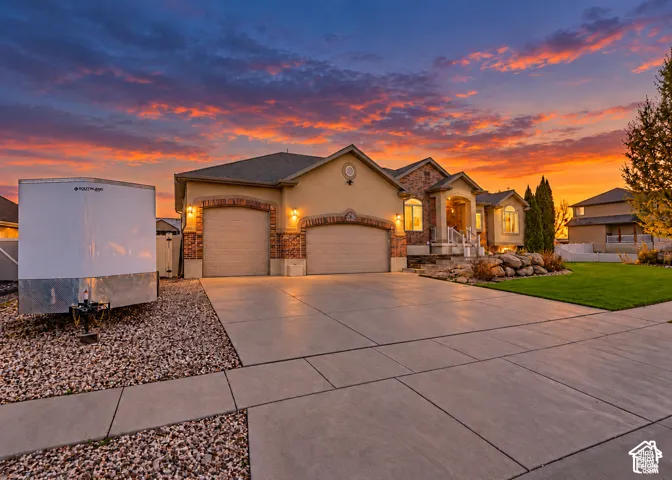 Exterior featuring a stucco and brick facade, an attached two-car garage, concrete driveway, and a landscaped front yard with rock features