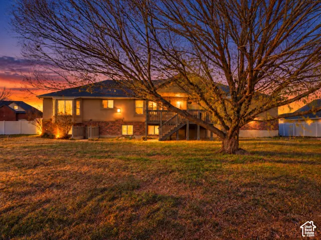 Rear exterior featuring a multi-level deck, stucco siding, and a brick foundation