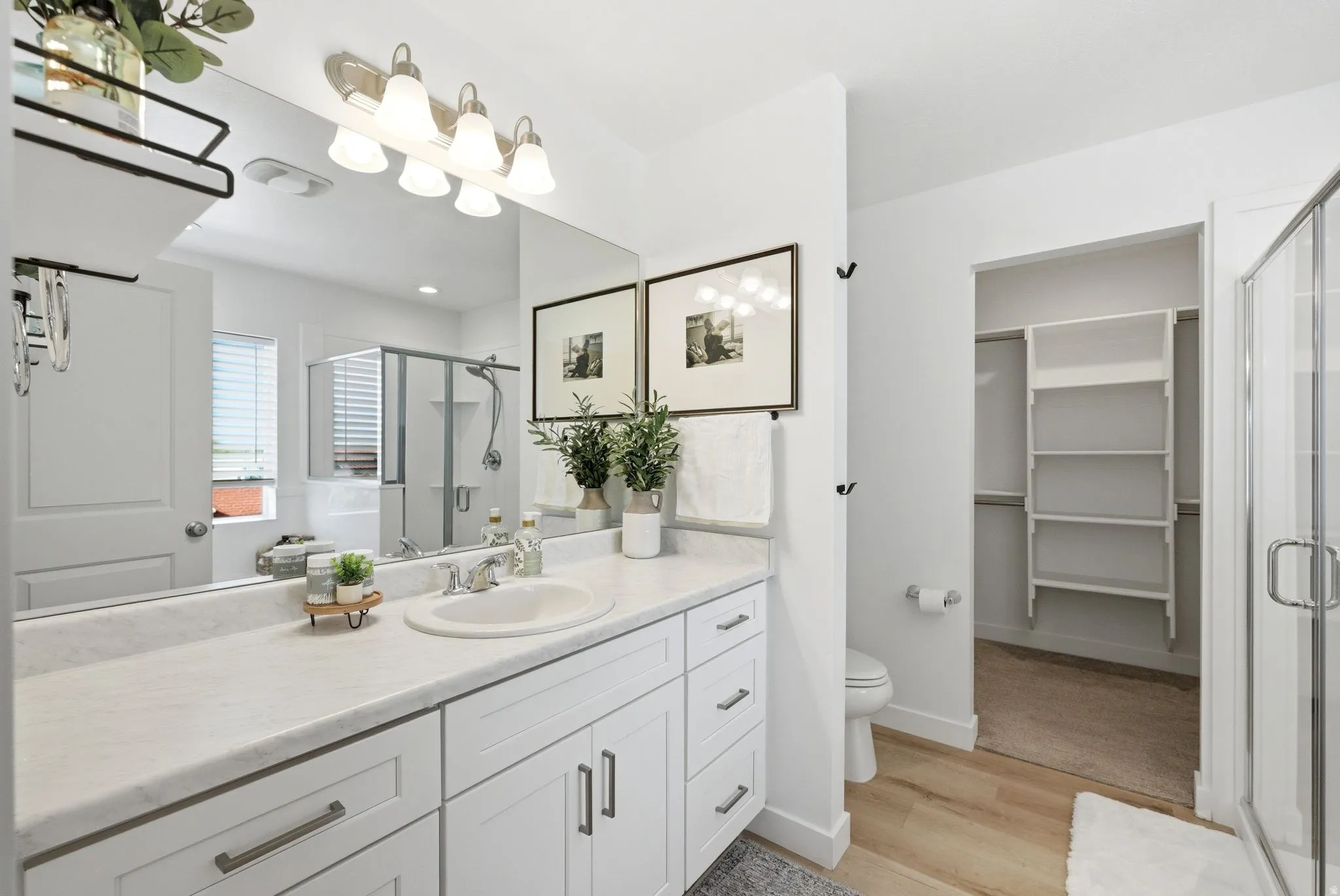 Full bath with vanity, a stall shower, a spacious closet, and light wood-style floors