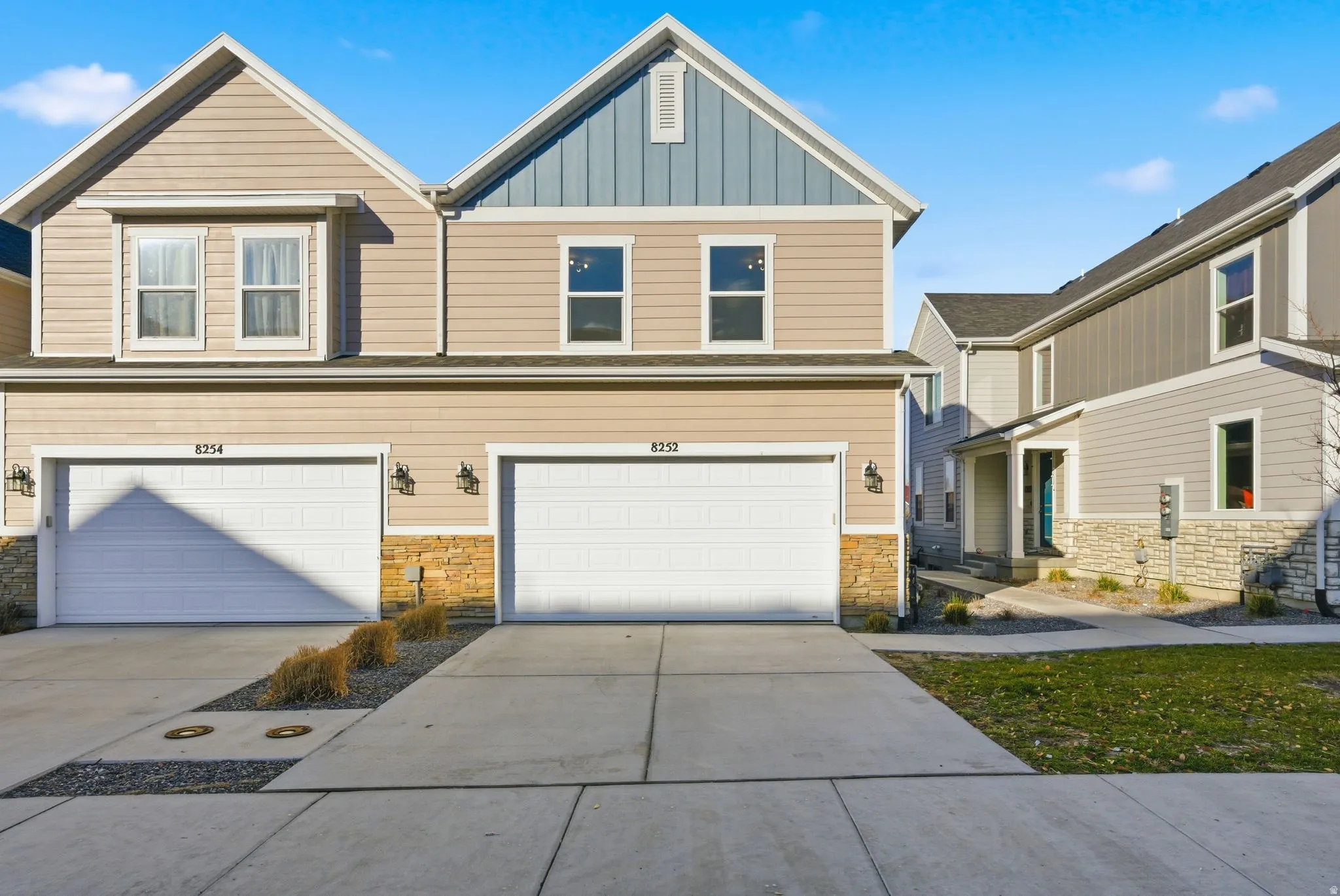 Craftsman-style house with stone siding, driveway, board and batten siding, and an attached garage