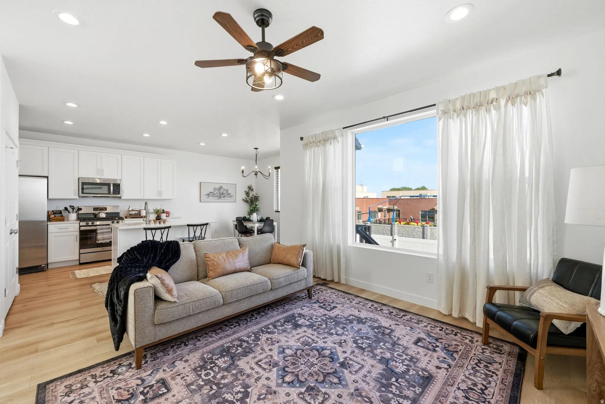 Living room featuring ceiling fan, light wood finished floors, and suspended lighting