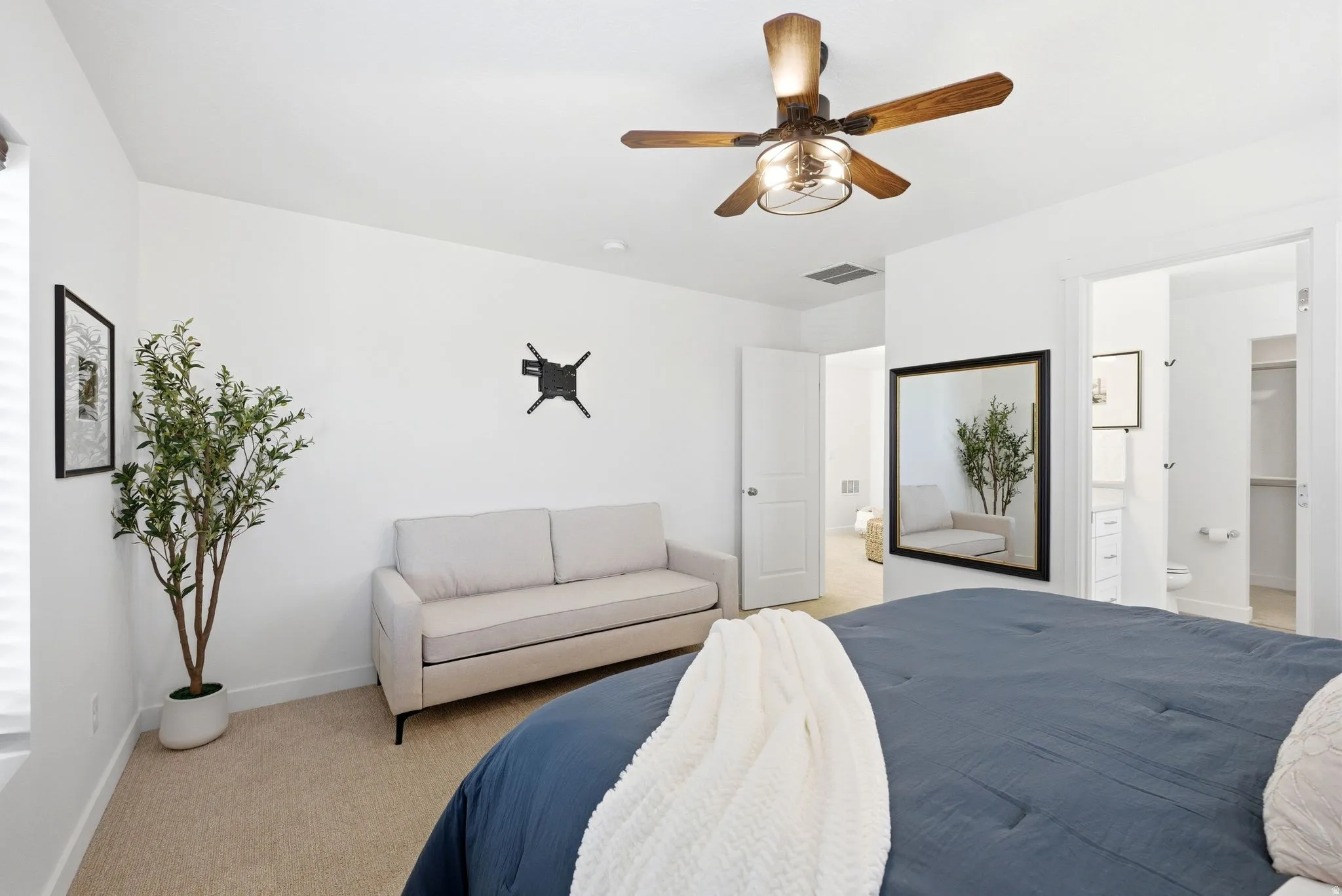 Bedroom with light colored carpet, ceiling fan, and ensuite bath
