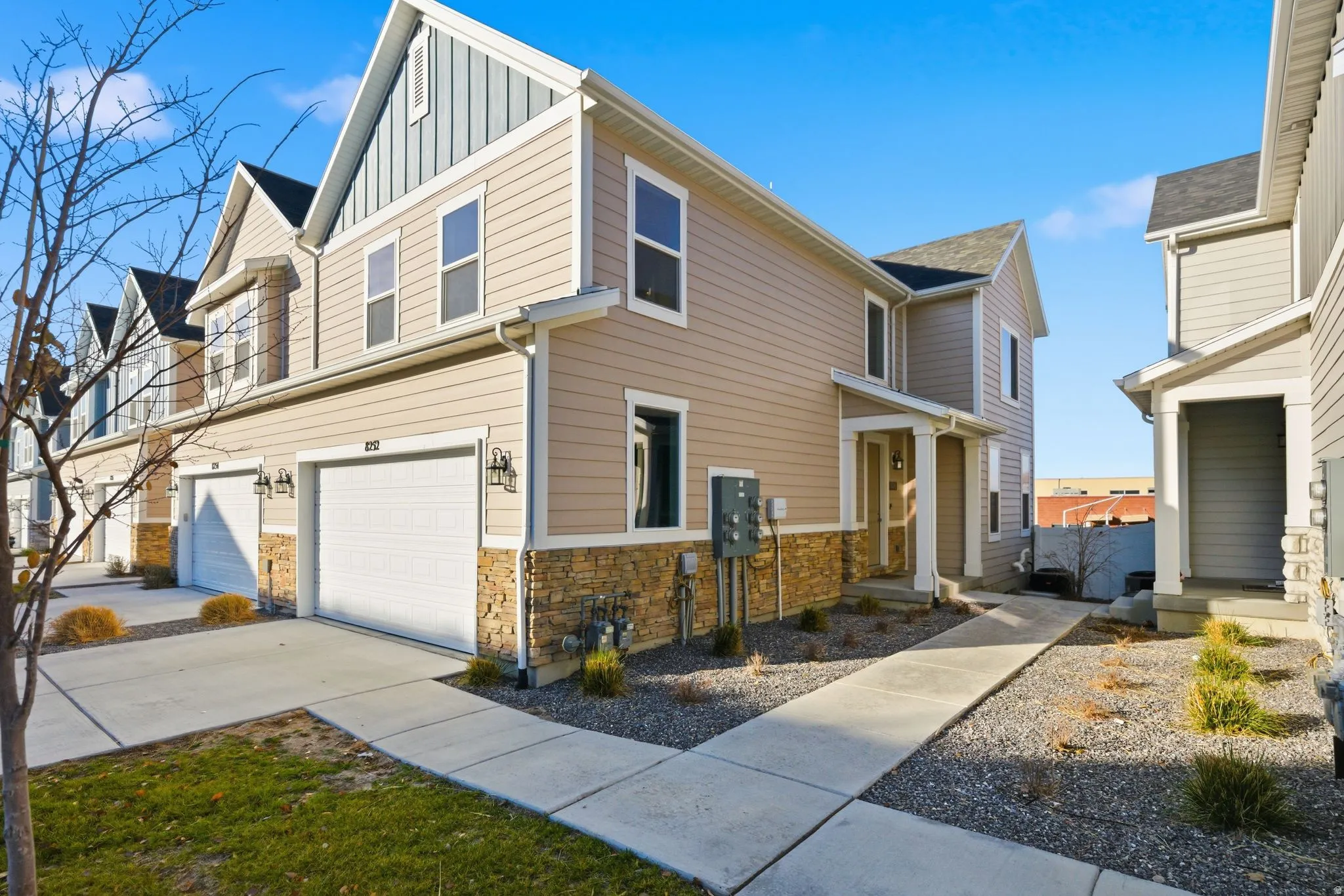 View of front of home featuring board and batten siding, stone siding, a garage, and concrete driveway