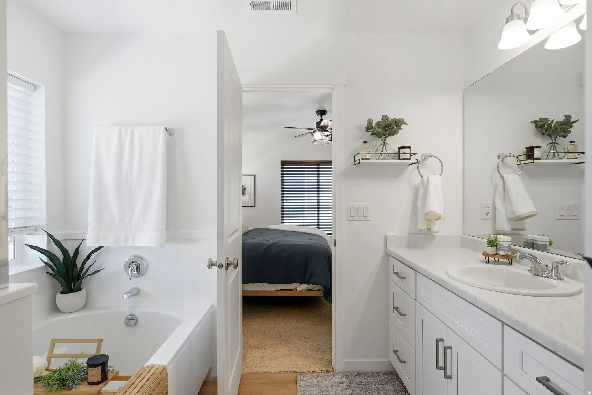 Full bath with vanity, ensuite bathroom, a bath, and light wood-style floors