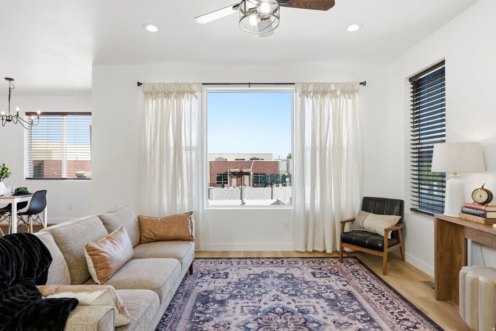 Living area with ceiling fan, light wood-style floors, suspended lighting, and plenty of natural light
