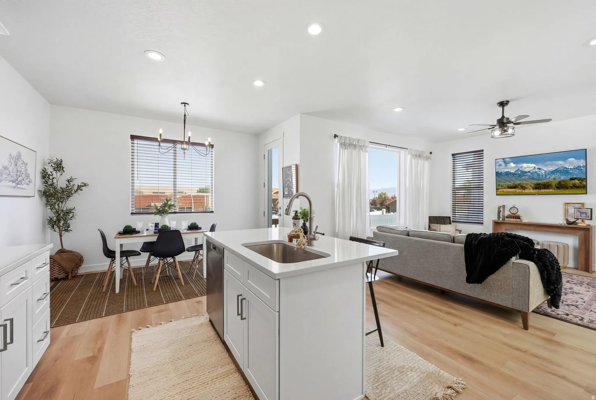 Kitchen with light wood finished floors, light stone countertops, a center island with sink, open floor plan, and plenty of natural light
