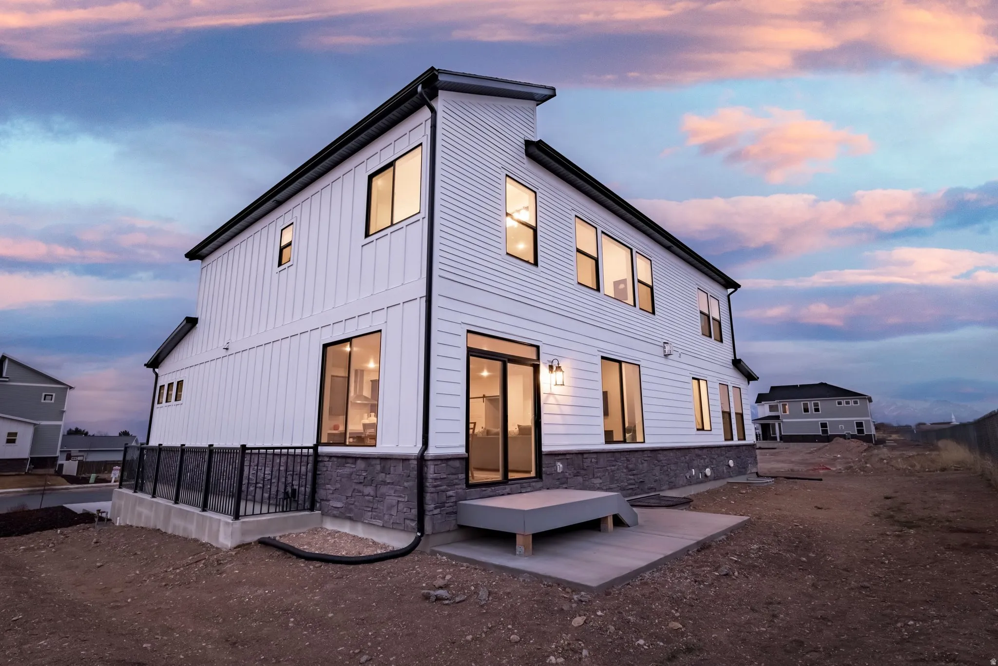 Back of house at dusk featuring stone siding and board and batten siding