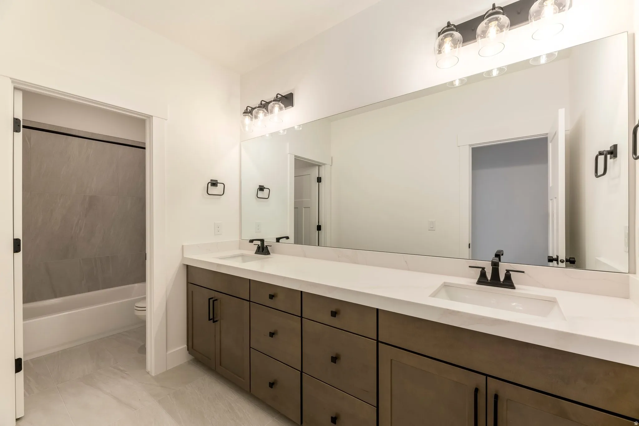 Full bathroom with double vanity and washtub / shower combination