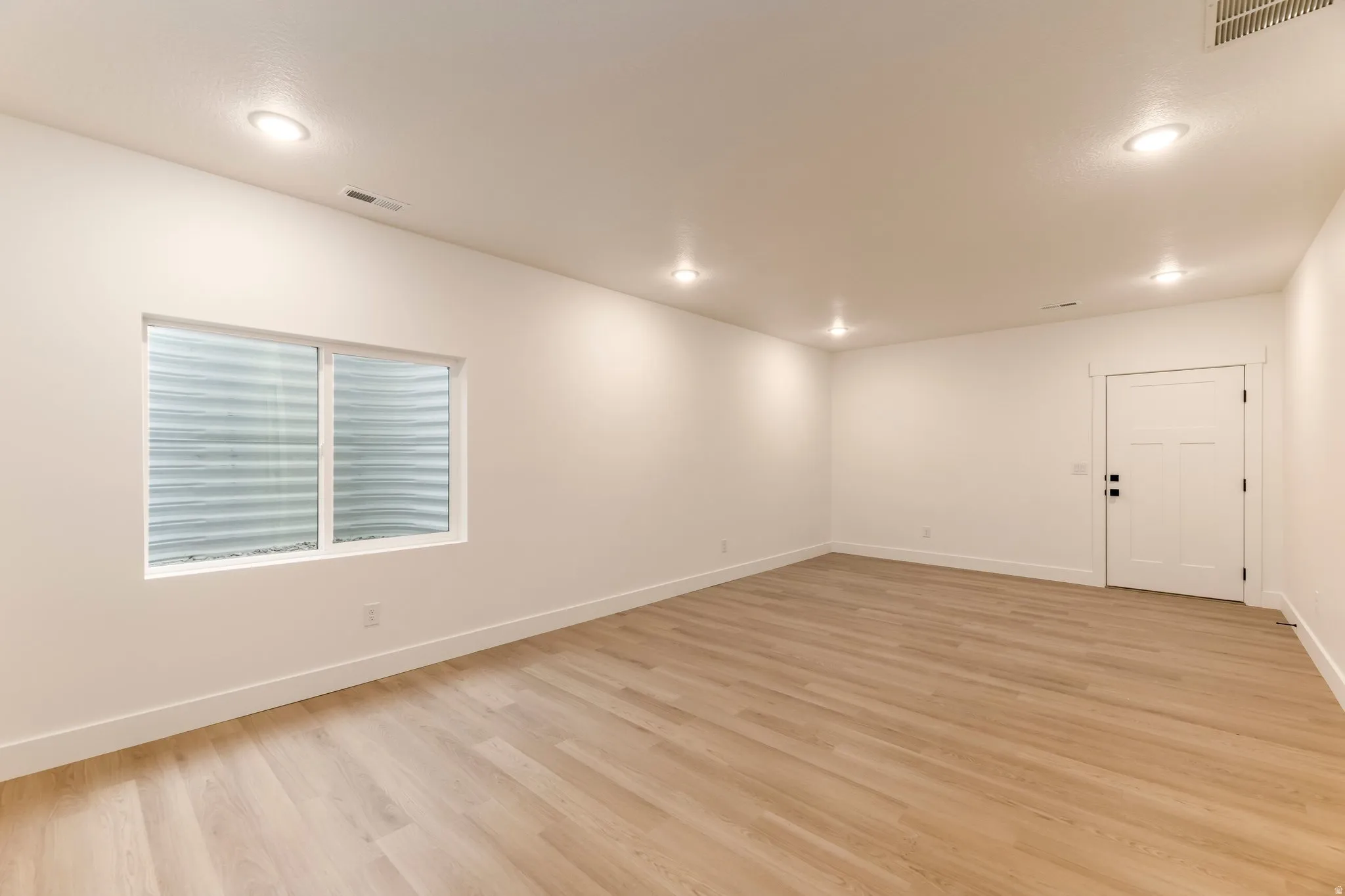 Empty room featuring light wood-style floors and recessed lighting