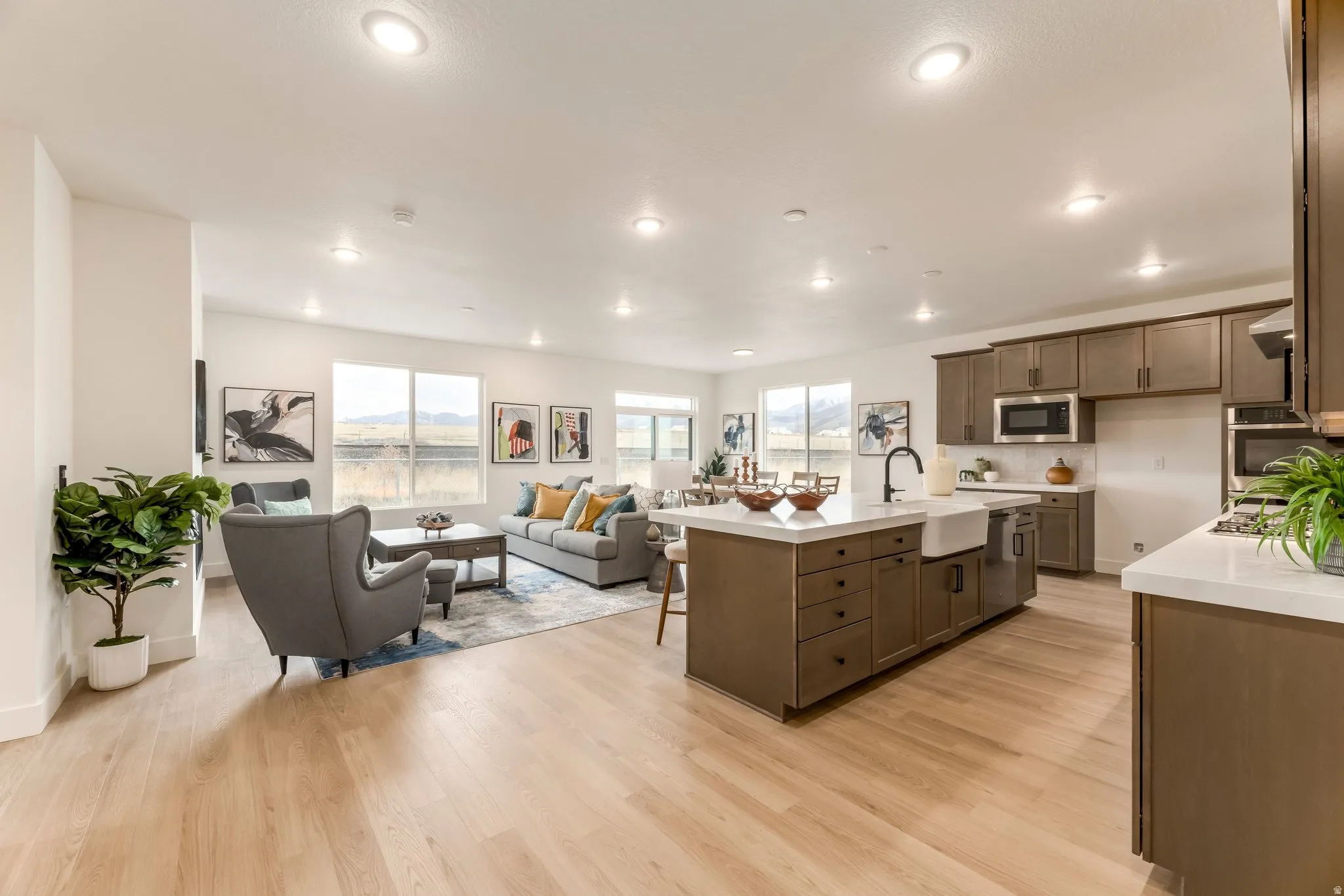 Kitchen with light wood finished floors, a breakfast bar, a center island with sink, open floor plan, and stainless steel appliances