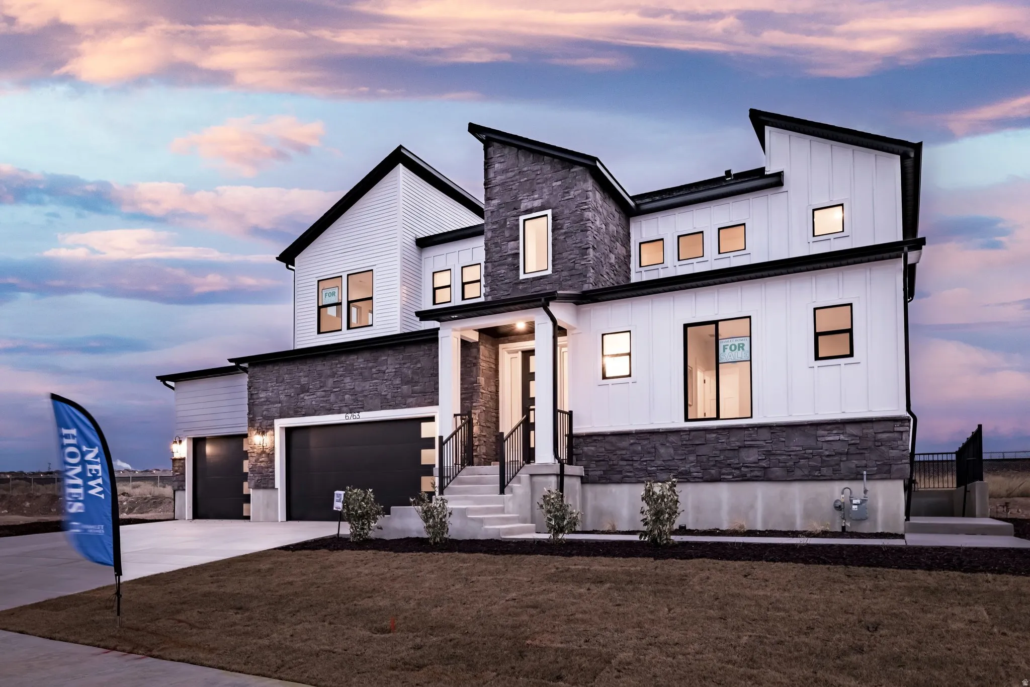 View of front of property featuring stone siding, board and batten siding, an attached garage, and driveway