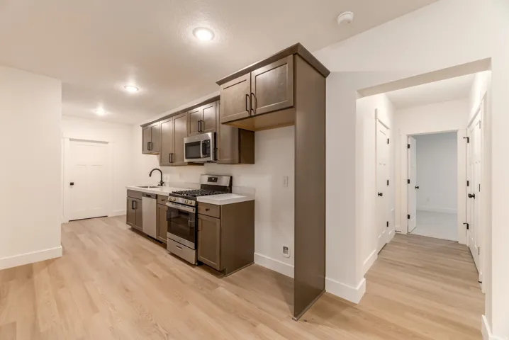 Kitchen with stainless steel appliances, light countertops, dark wood finish cabinets, and light wood-style flooring