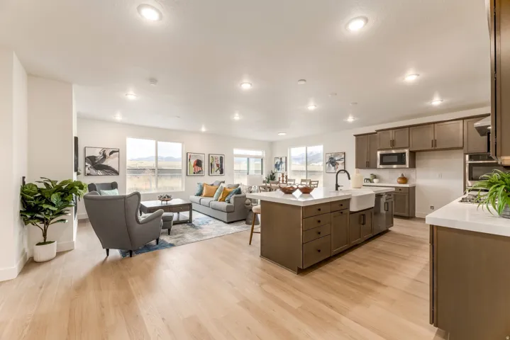 Kitchen with light wood finished floors, a breakfast bar, a center island with sink, open floor plan, and stainless steel appliances