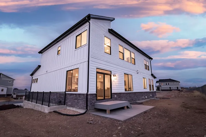 Back of house at dusk featuring stone siding and board and batten siding