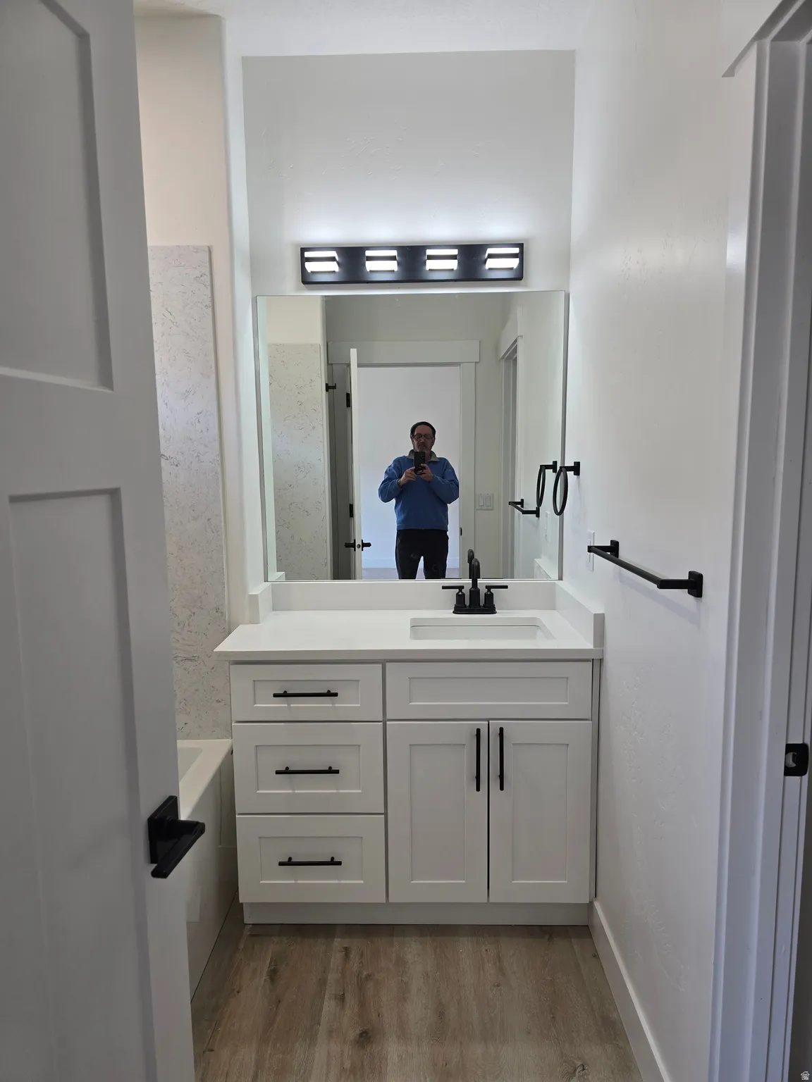 Bathroom featuring a bathtub, vanity, and light wood-style floors