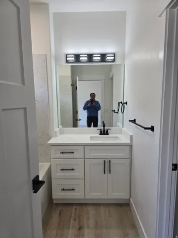Bathroom featuring a bathtub, vanity, and light wood-style floors