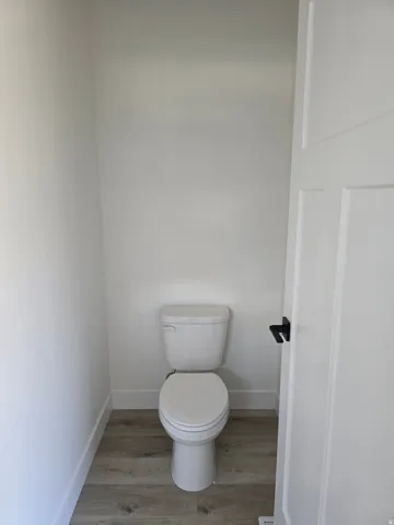 BathroomPrivate water closet featuring toilet and light wood-style floors