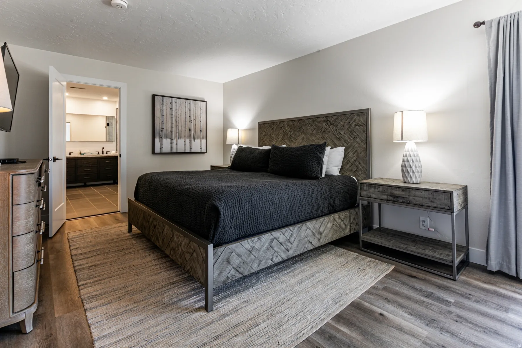 Bedroom with wood finished floors, a textured ceiling, and ensuite bath