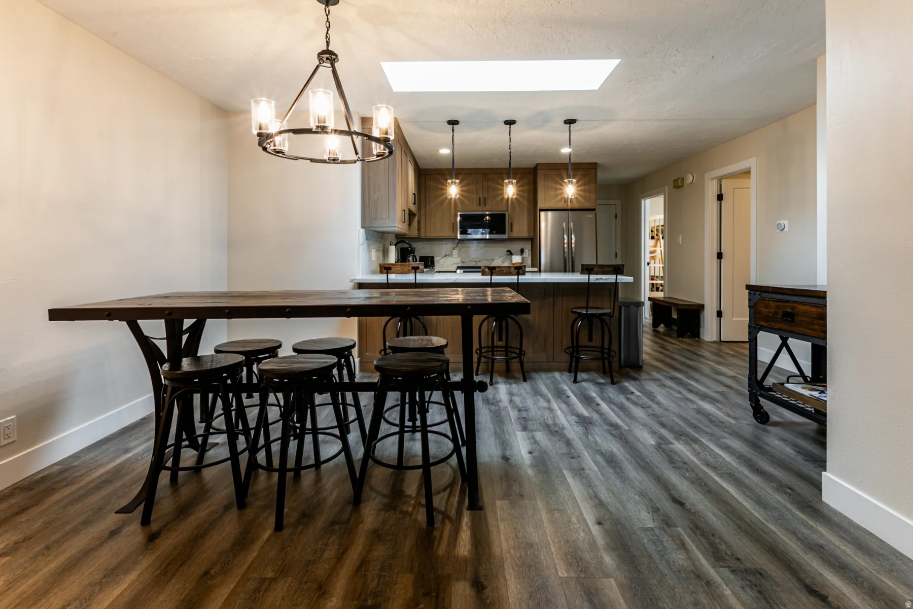 Dining room with a skylight, a chandelier, dark wood-style floors, and a textured ceiling