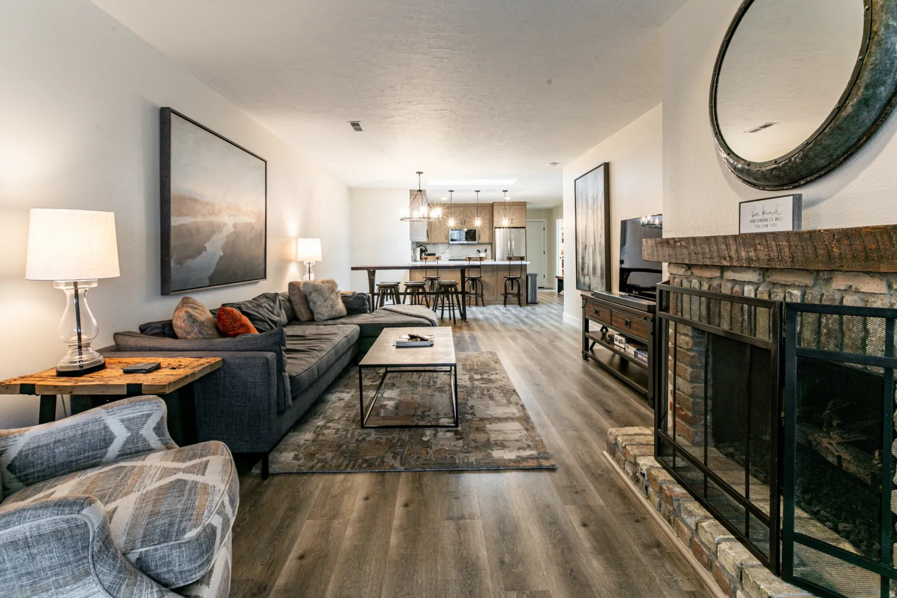 Living area with dark wood-type flooring, a textured ceiling, a chandelier, and a brick fireplace
