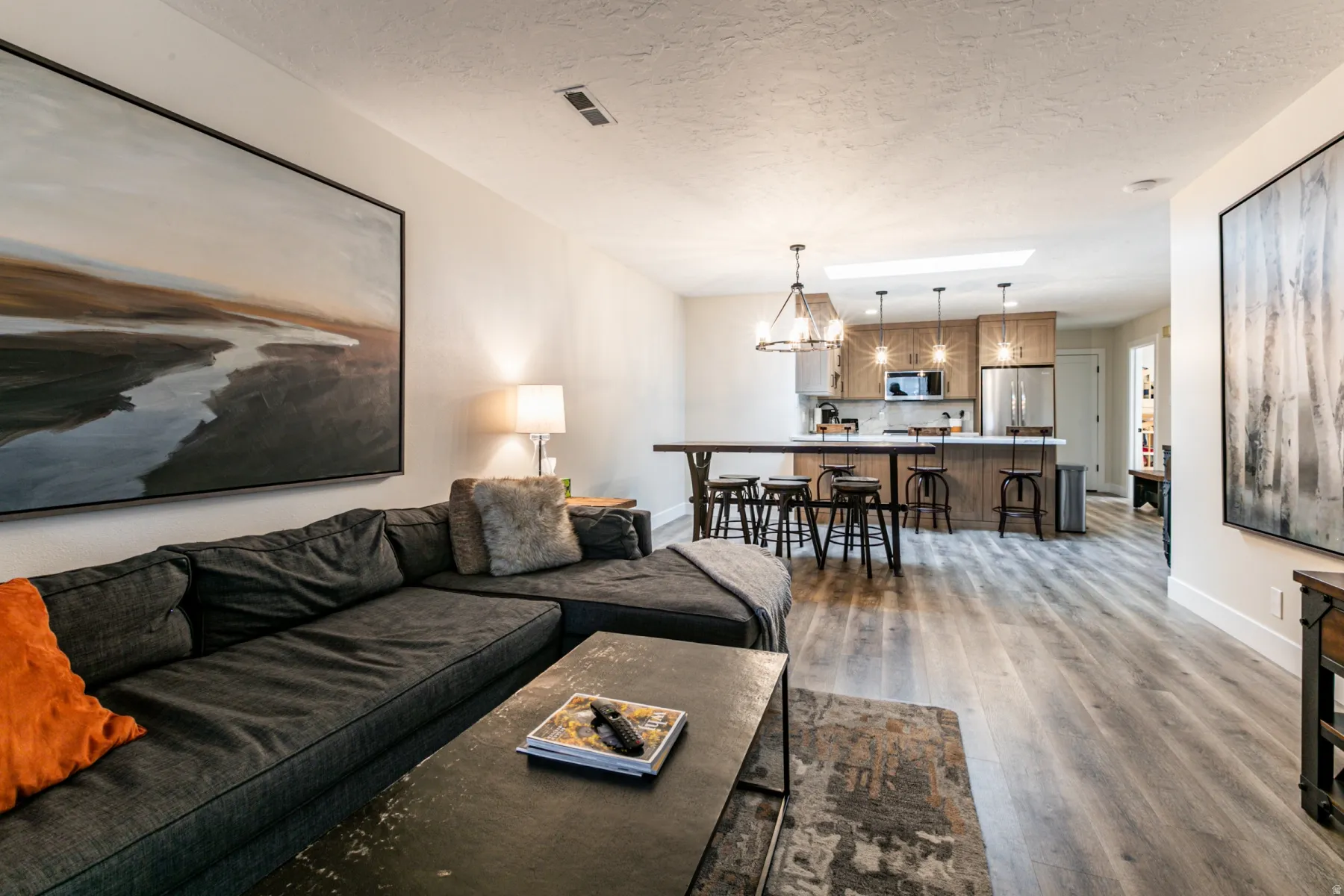 Living area with a textured ceiling, a chandelier, and light wood-style floors