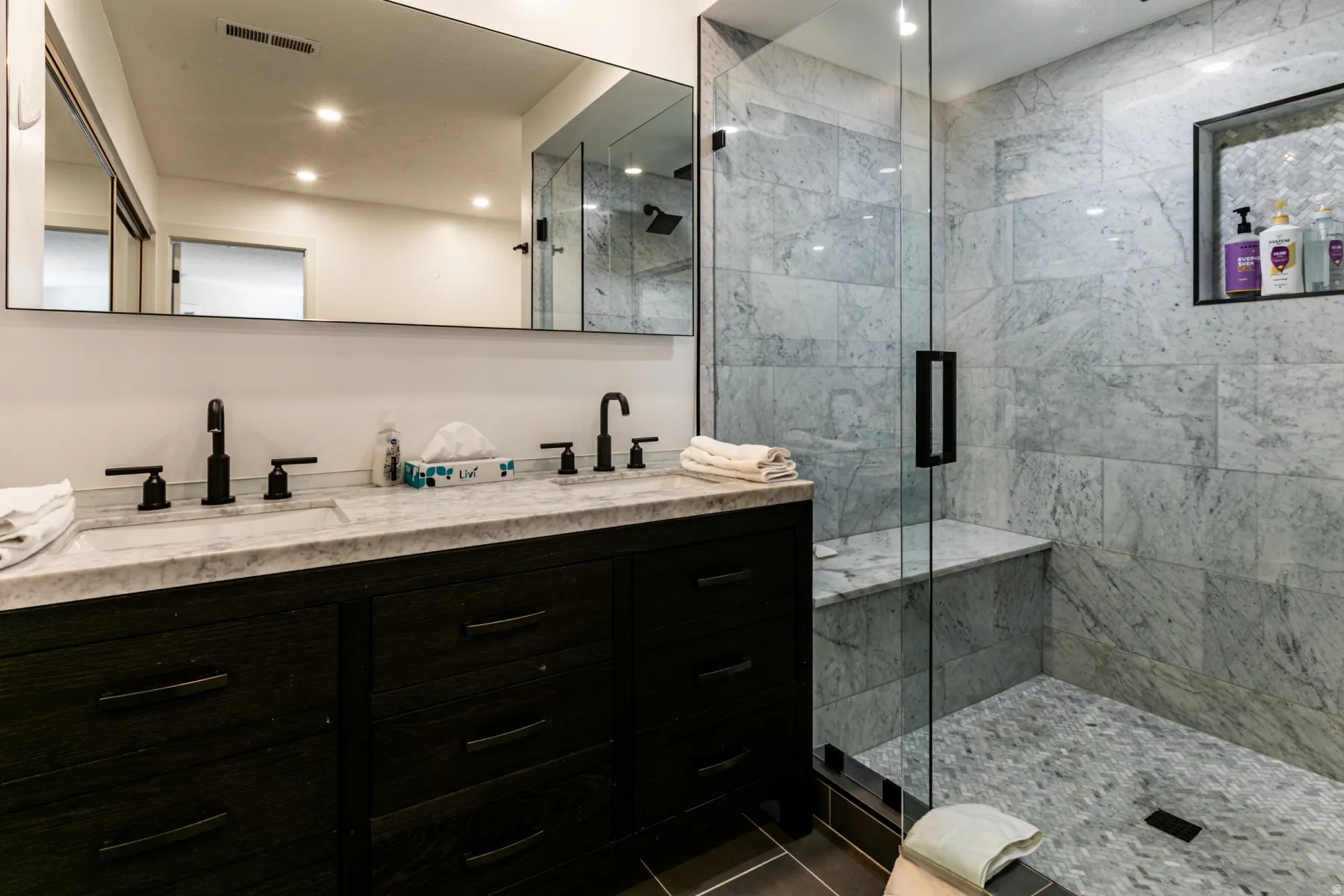 Bathroom featuring double vanity, a marble finish shower, recessed lighting, and dark tile patterned flooring