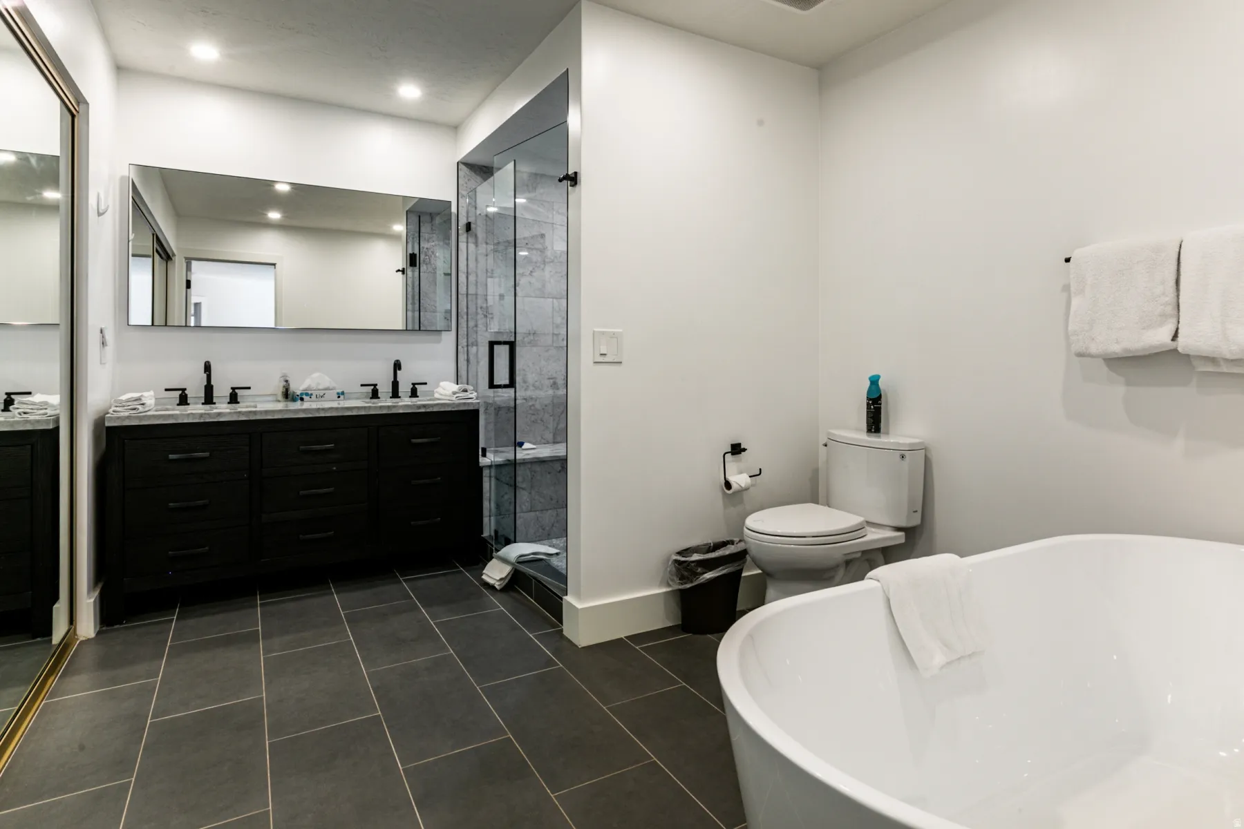 Full bathroom with a soaking tub, double vanity, a shower stall, dark tile patterned floors, and recessed lighting
