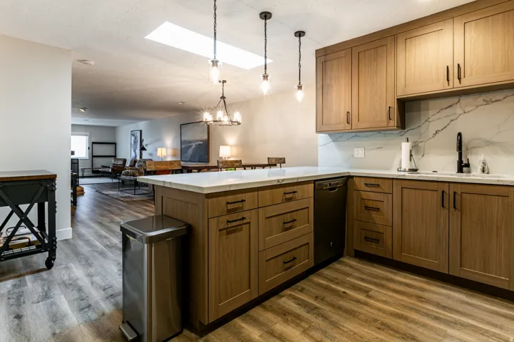 Kitchen featuring brown cabinets, a skylight, a peninsula, a chandelier, and open floor plan