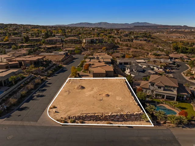 Aerial view of residential area with property boundaries highlighted and a mountainous background