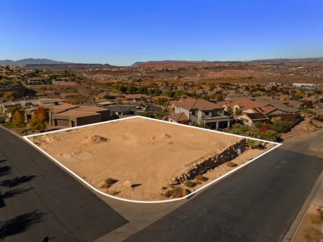 Aerial perspective of suburban area with property parcel outlined and a mountainous background
