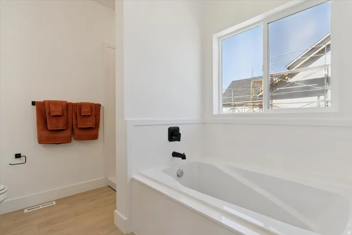 Full bath with a garden tub and light wood-style floors