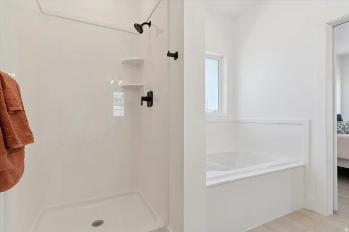 Full bathroom with connected bathroom, a bath, wood finished floors, and a stall shower