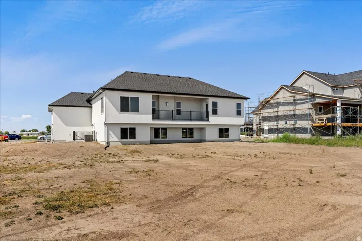 Rear view of property with a balcony, stucco siding, and roof with shingles