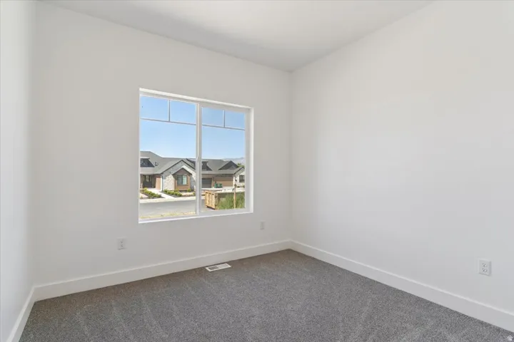Spare room with dark colored carpet and a residential view