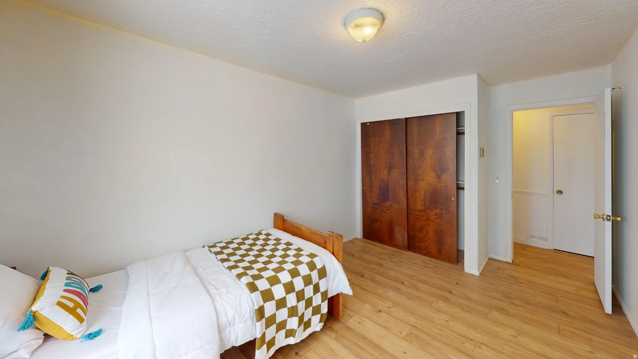 Bedroom featuring light wood-type flooring, a textured ceiling, and a closet