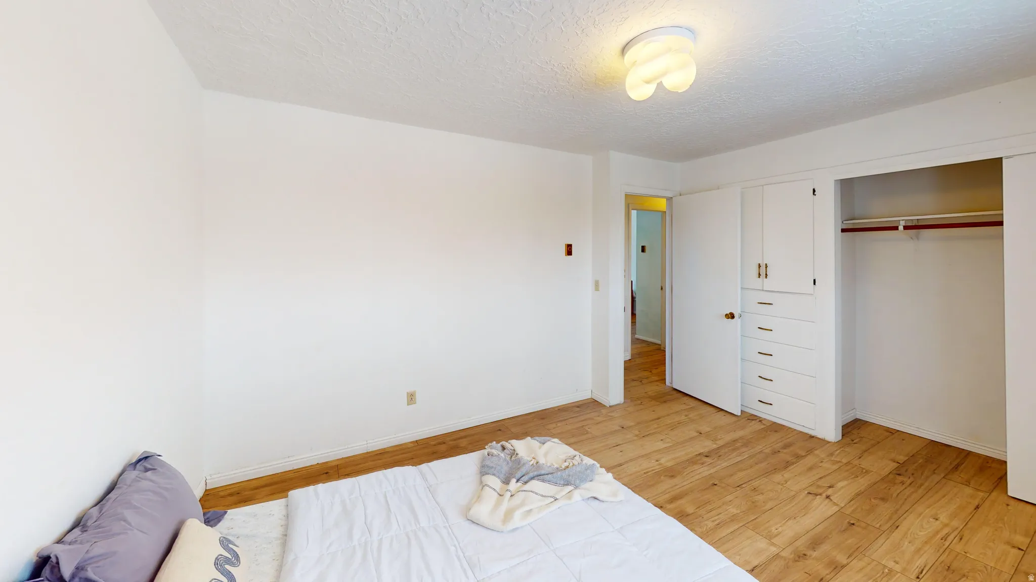 Bedroom featuring light wood-style floors, a textured ceiling, and a closet