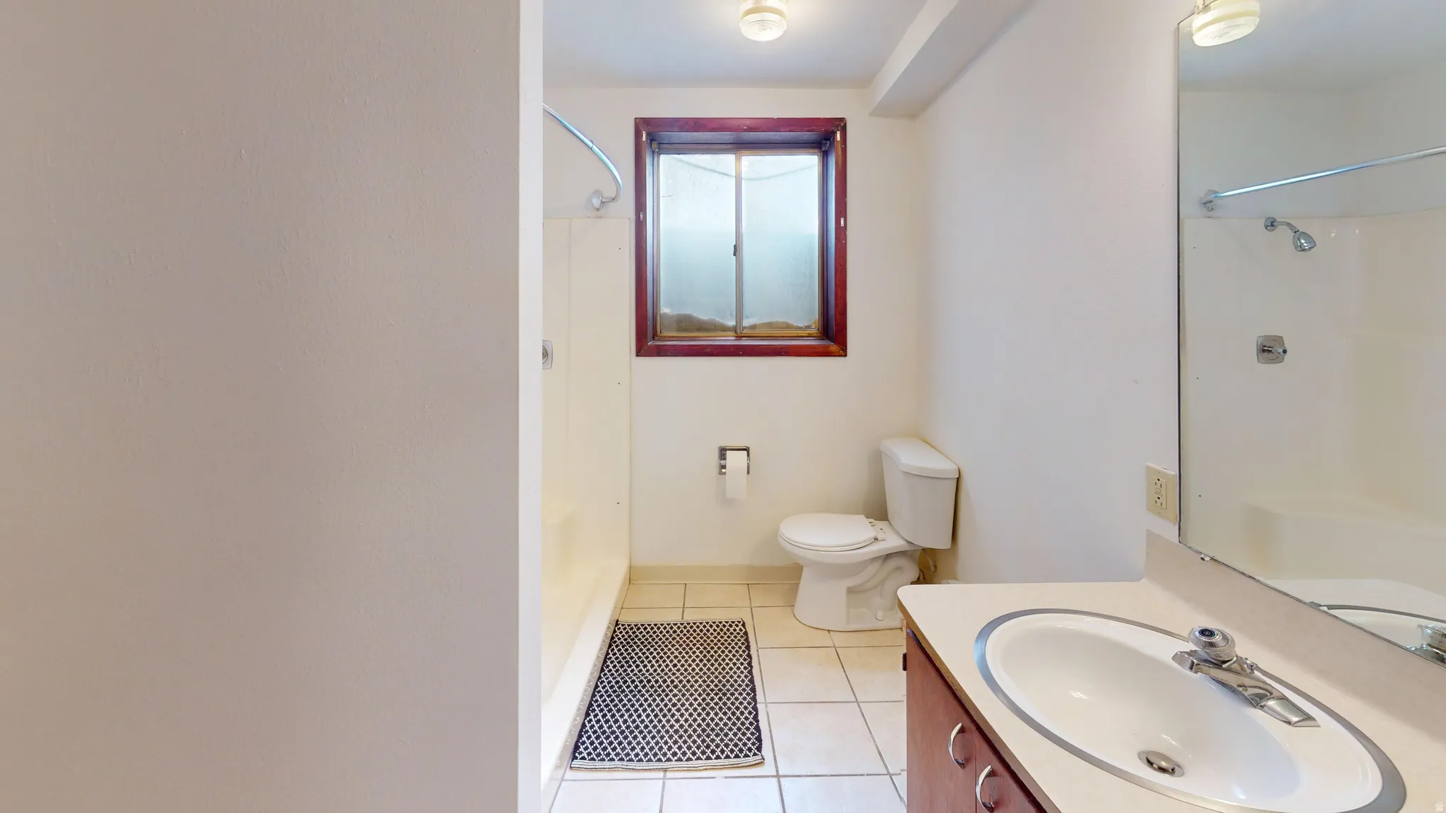 Bathroom featuring vanity, light tile patterned floors, and  shower combination