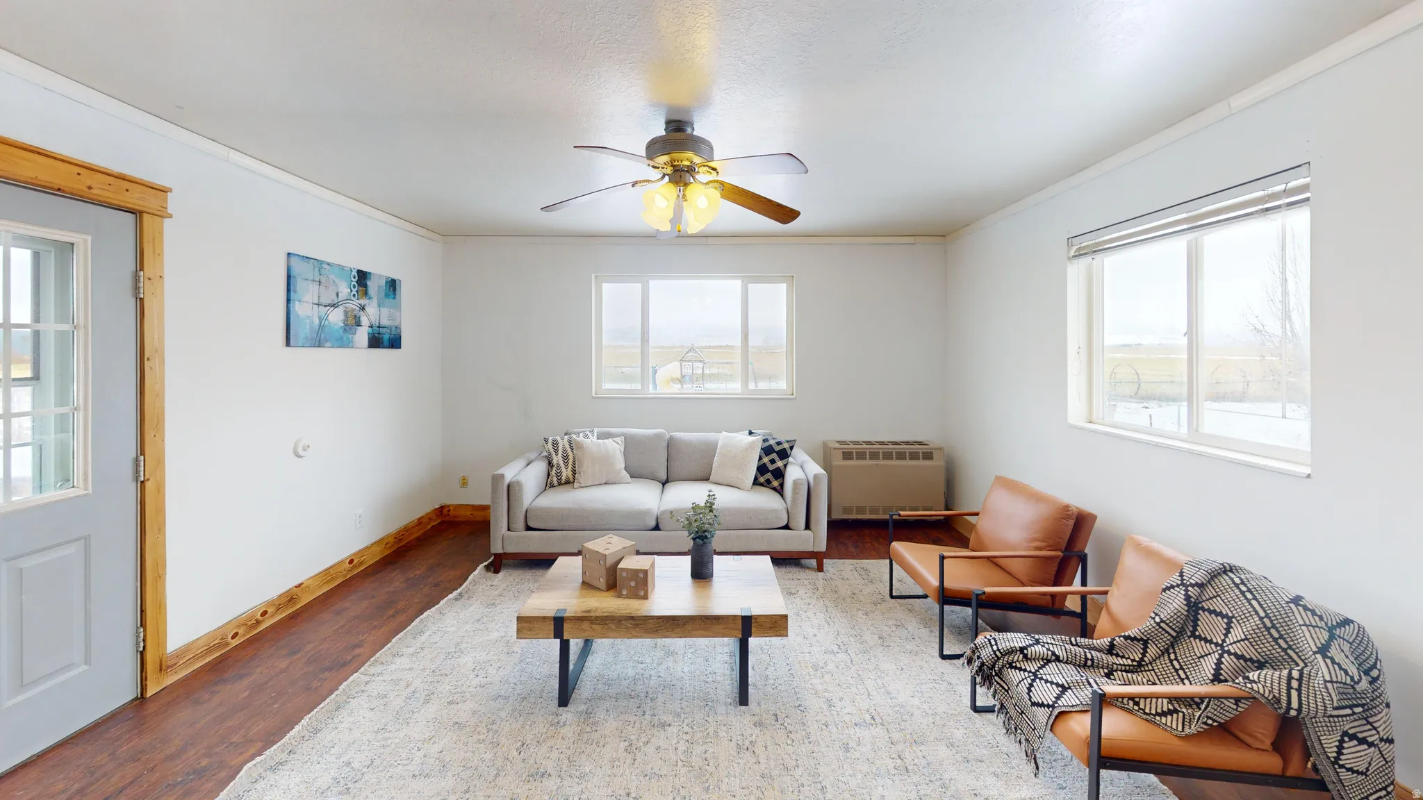 Living area with ceiling fan, wood finished floors, heating unit, and ornamental molding