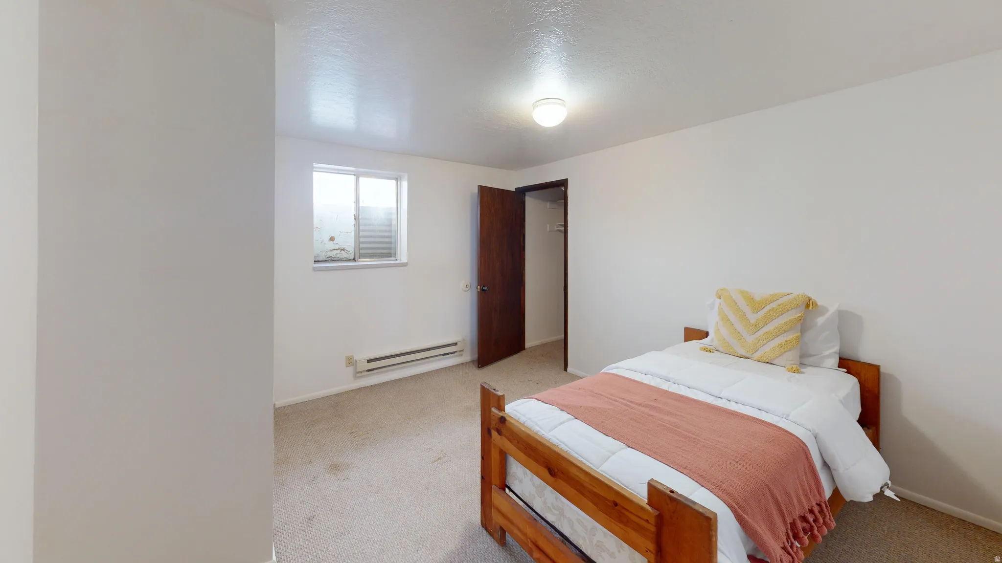 Carpeted bedroom with baseboard heating and a textured ceiling