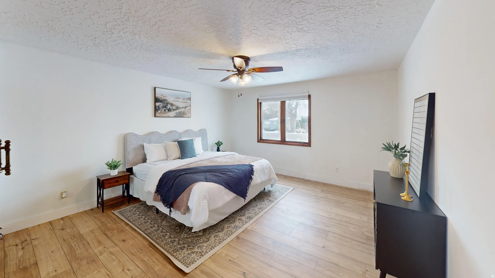 Bedroom featuring light wood-type flooring, a textured ceiling, and ceiling fan