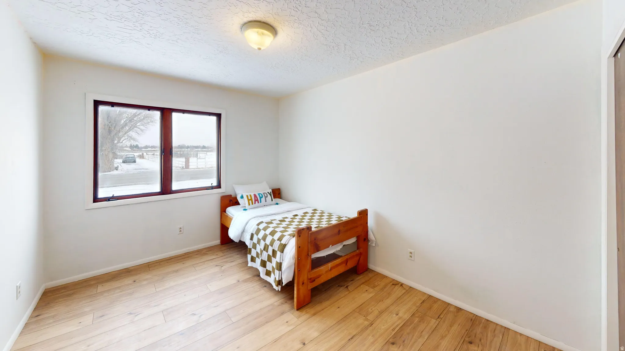 Bedroom with light wood finished floors and a textured ceiling