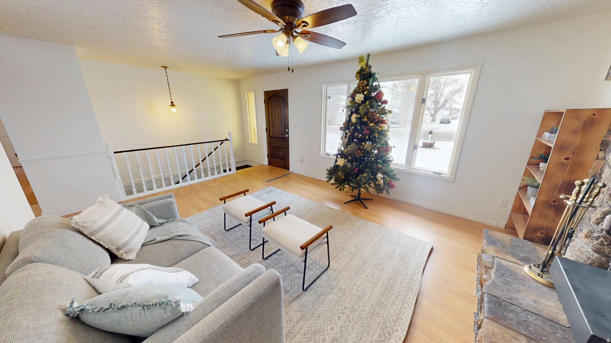 Living room featuring light wood-style floors, a textured ceiling, and a ceiling fan