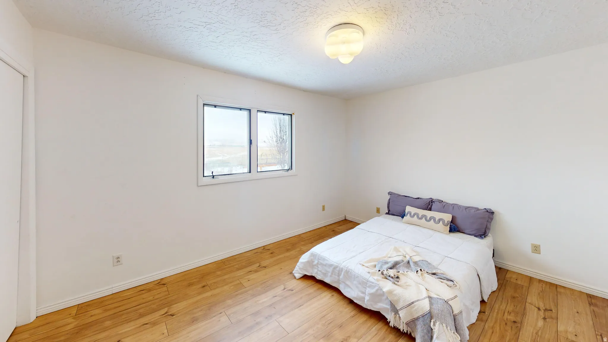 Bedroom with light wood-style floors and a textured ceiling