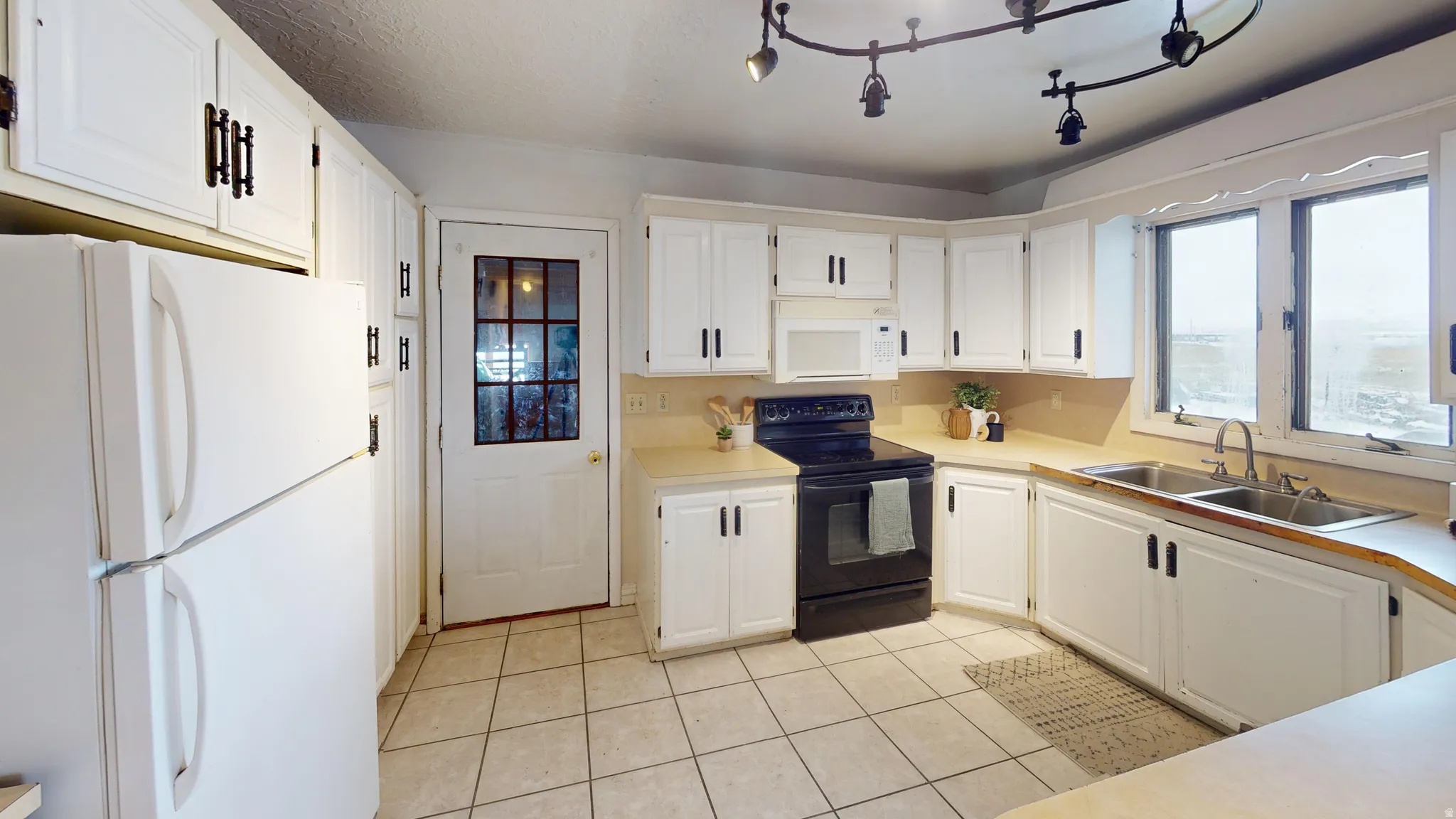 Kitchen featuring white appliances, white cabinets, light countertops, and light tile patterned floors