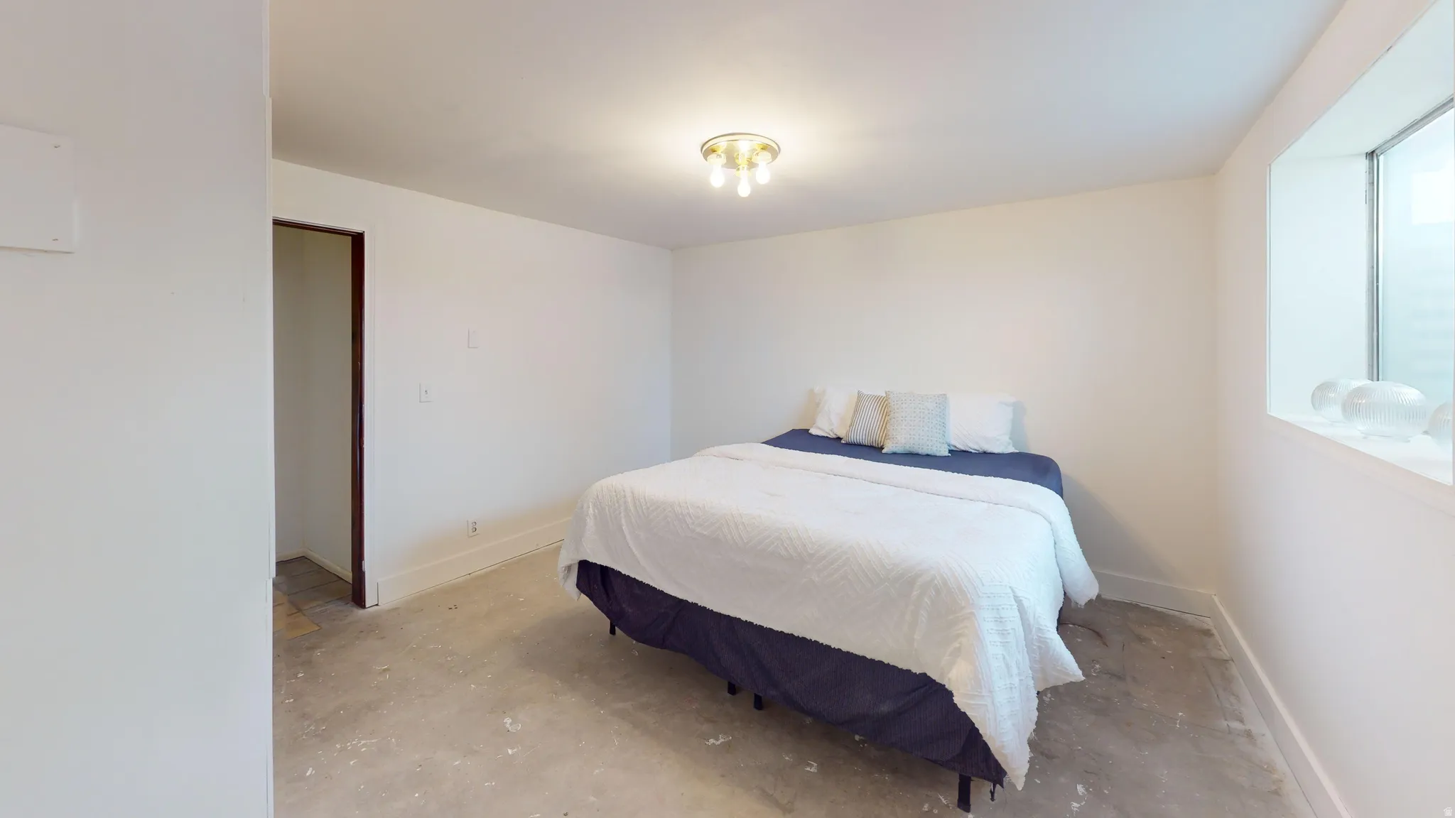 Bedroom with unfinished concrete flooring and baseboards
