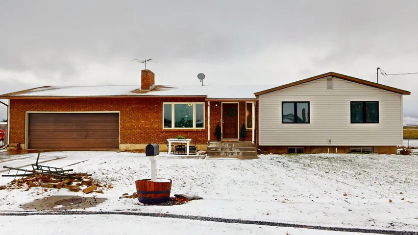 View of front facade featuring brick siding, a chimney, and a garage