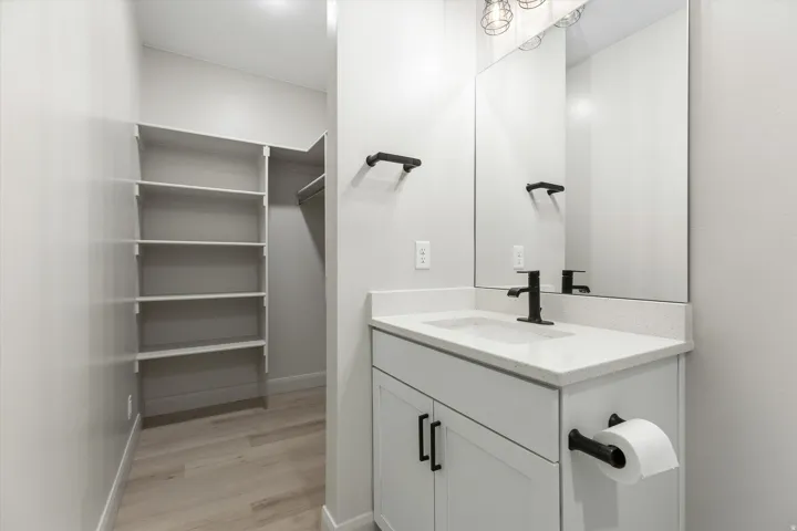 Light-colored wood-finish flooring extending into a built-in closet system with shelving and hanging rod