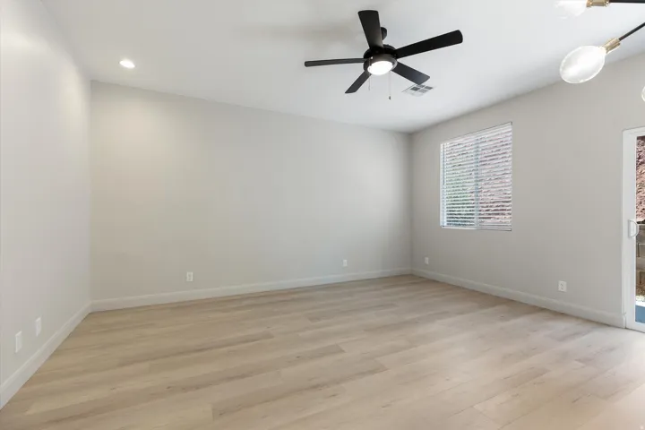 Light wood-finish flooring, recessed lighting, ceiling fan with integrated light, window with blinds, and a glass-paneled door